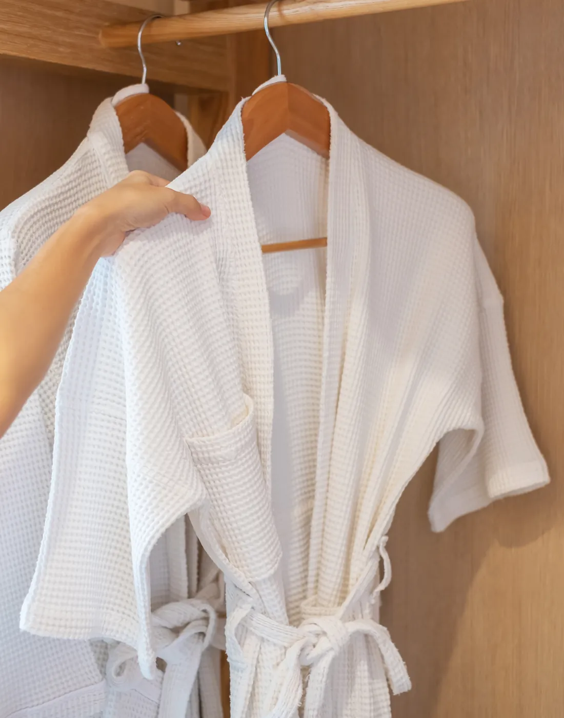 Batas de baño blancas colgadas en el placard de una habitación de hotel
