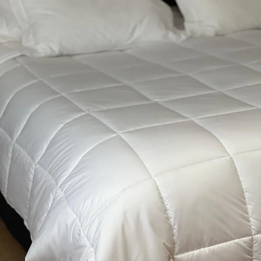 Acolchado blanco con pespunte cuadriculado extendido sobre la cama