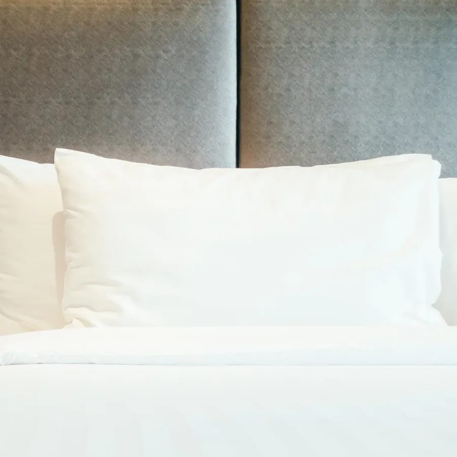 Almohadas con funda blanca sobre la cabecera de una cama tendida